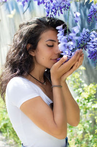 Side view of young woman smelling flowers on plants