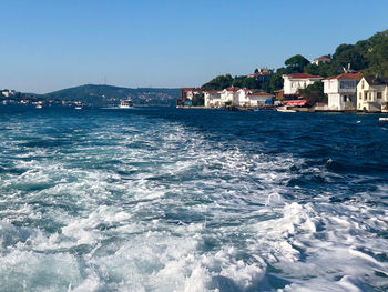 Scenic view of sea by buildings against clear blue sky