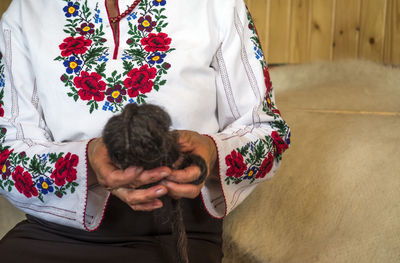 Midsection of woman holding ball of wool at home