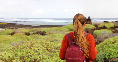 Rear view of woman with backpack standing against sea