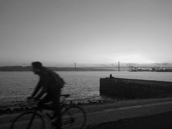 Man riding bicycle on suspension bridge over river