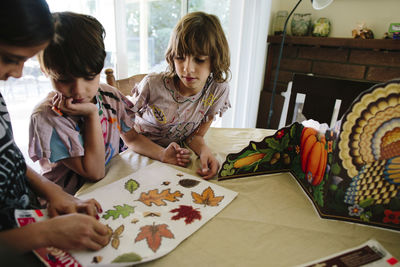 Girl with siblings removing leaves labels at table