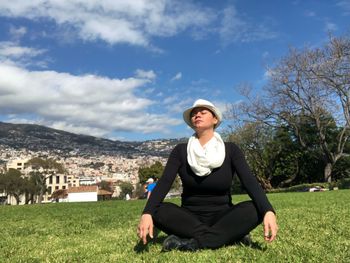 Woman sitting on grassy field during sunny day