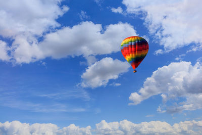 Flying beautiful multicolored hot air balloon with a basket of tourists on the background of the sky