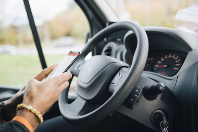 Cropped image of man using mobile phone while sitting in delivery van