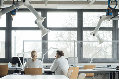 Scientist with colleague sitting at desk in laboratory