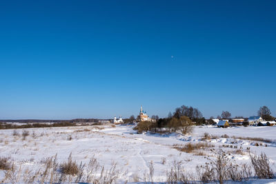 Scenic view of snow covered land against clear blue sky