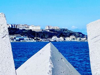 View of buildings by sea against blue sky
