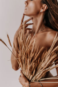 Half-naked woman covers herself with dry ears of corn