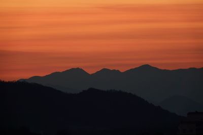 Scenic view of silhouette mountains against romantic sky at sunset