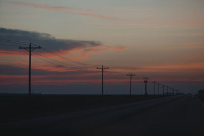 Silhouette electricity pylons against sky during sunset