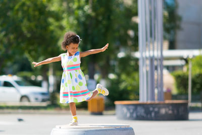 Full length of cheerful girl standing on footpath