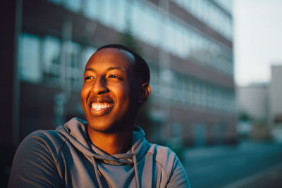 Close-up of smiling young man looking away in city