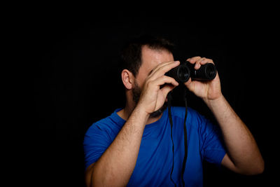 Man holding binoculars against black background