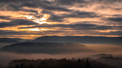 Scenic view of silhouette mountains against orange sky