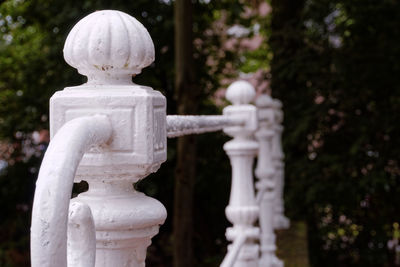 Close-up of white railing against trees