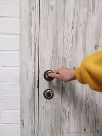 Rear view of human hand opens a wooden door