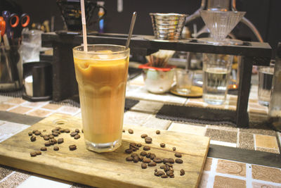 Close-up of drink glass and roasted coffee beans on cutting board at cafe