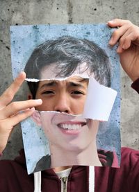 Close-up portrait of boy holding torn portrait 