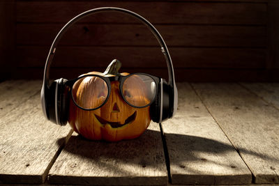 Anthropomorphic face of pumpkin wearing headphones on table