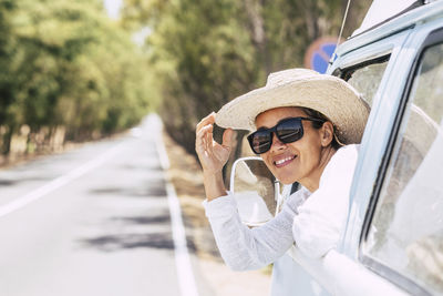 Smiling woman wearing hat looking through car window