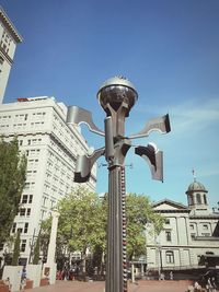 Low angle view of street light by building against sky