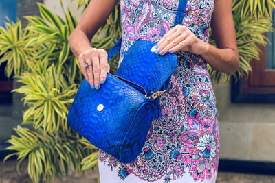 Midsection of woman standing against blue wall