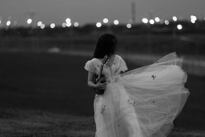 Rear view of woman standing against illuminated lights