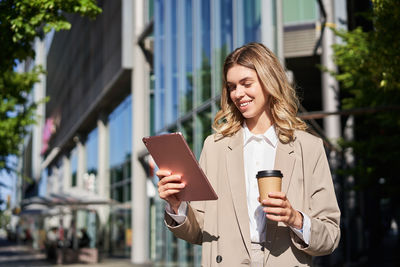 Portrait of young woman using digital tablet in city