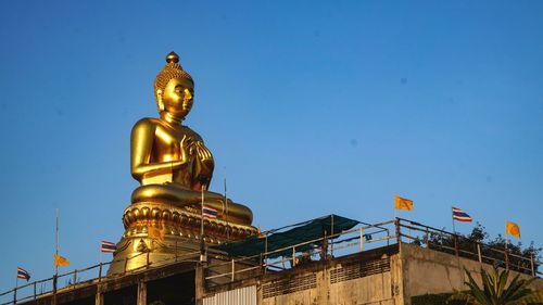 Low angle view of statue against blue sky and building