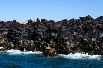 Rocks in sea against clear sky