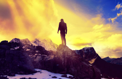 Man standing on rock against sky during sunset