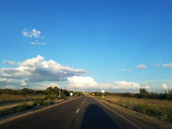 Road by landscape against blue sky