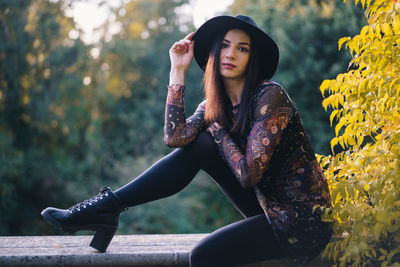 Young woman looking away while sitting on plant