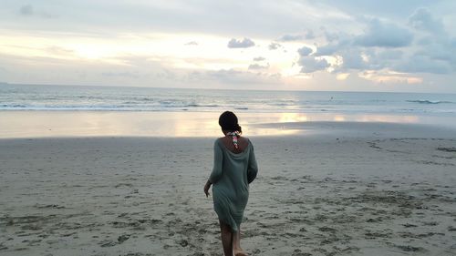 Rear view of woman walking on sand at beach