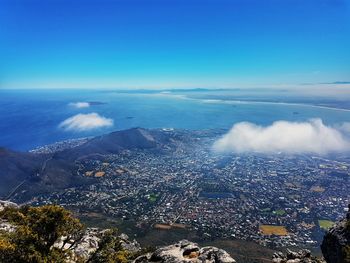 High angle view of city by sea against blue sky