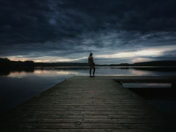 Rear view of man standing on jetty in lake