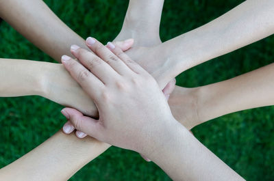 Cropped image of female friends stacking hands over field