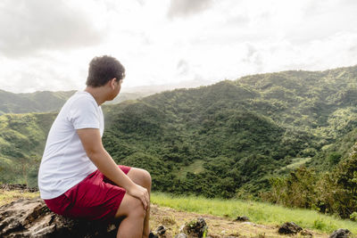 Side view of man sitting on mountain