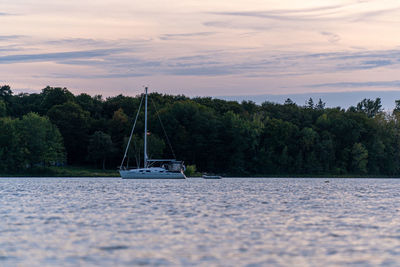 Sailboat sailing on sea against sky during sunset