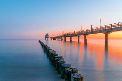 Pier over sea against sky during sunset