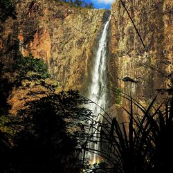 Scenic view of waterfall in forest against sky