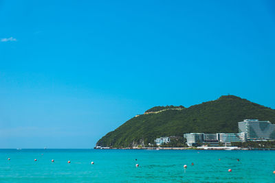 Scenic view of sea and island against blue sky