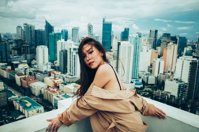 Young woman with cityscape against sky