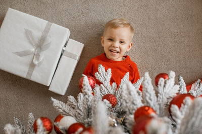 Happy funny child is laughing lying on the floor under the christmas tree with gifts