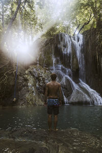 Man standing near waterfall