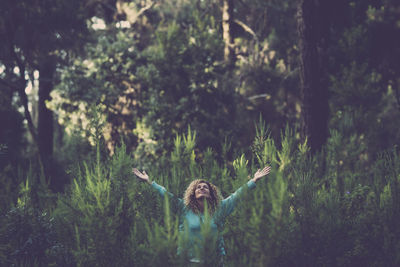 Woman standing by plants in forest