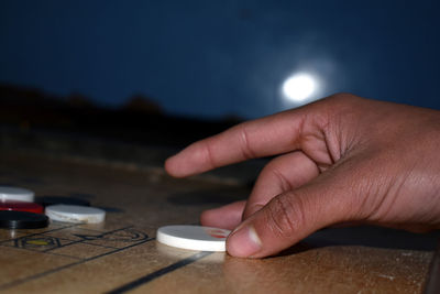 Close-up of person holding camera on table against sky