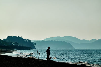 Man standing on beach against clear sky