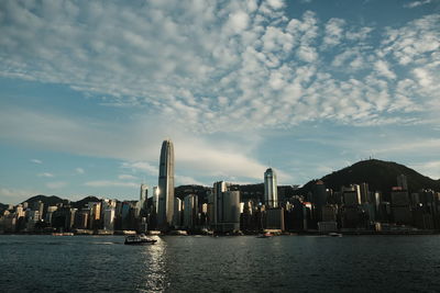 Sea by modern buildings against sky in city